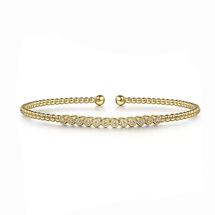 Beaded gold bangle bracelet featuring a row of bezel-set diamonds.