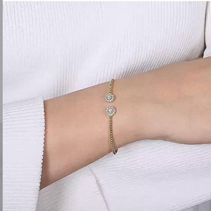 14K gold split cuff bracelet adorned with sparkling diamond flower accents, shown on a wrist.