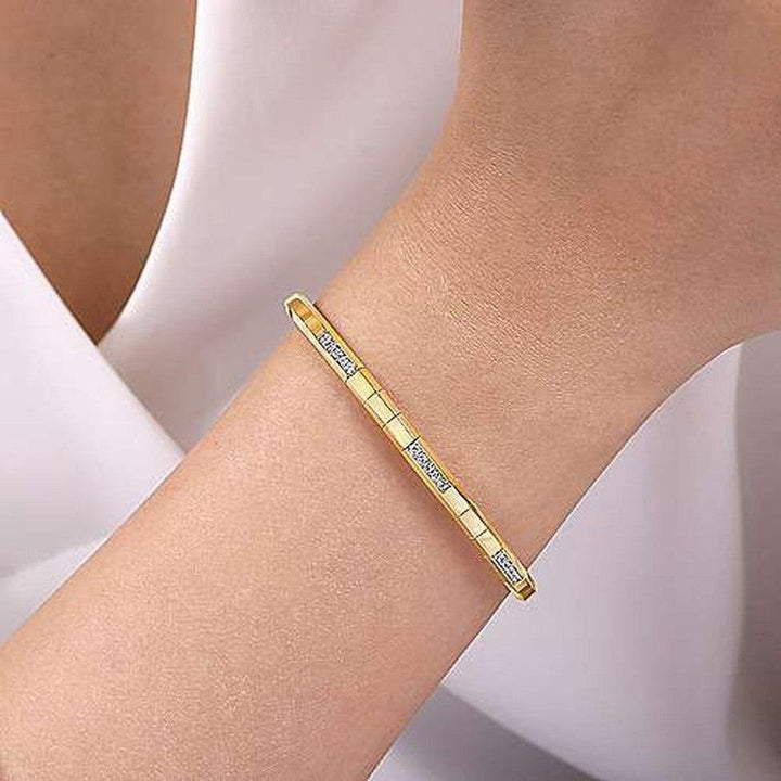 Gold cuff bracelet with diamonds, on a wrist.