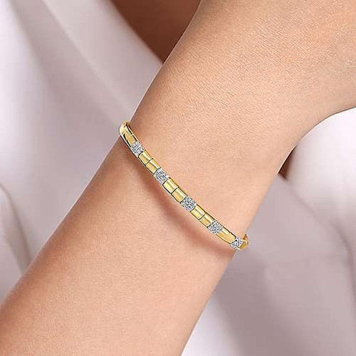 Gold cuff bracelet adorned with sparkling diamonds, elegantly displayed on a wrist.