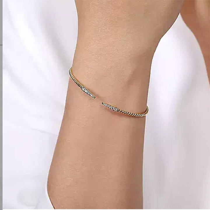 14K gold cuff bracelet with pave diamond accents, worn on a wrist.