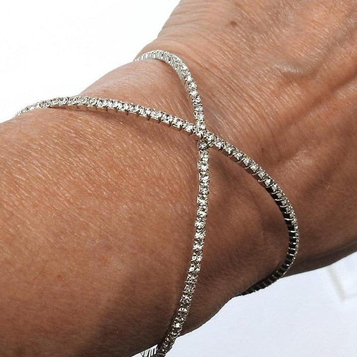 Sparkling crystal cuff bracelet with crisscross design, worn on a wrist.
