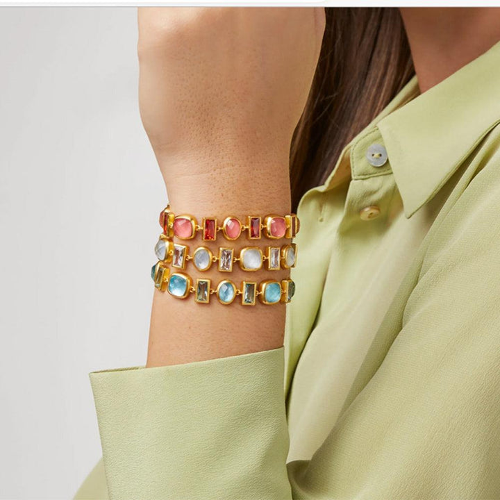 Gold bracelet featuring three colorful gemstone rows on a wrist.