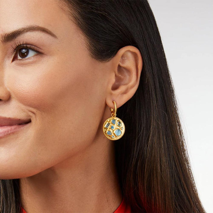 Gold hoop earrings with a circular blue gemstone charm.