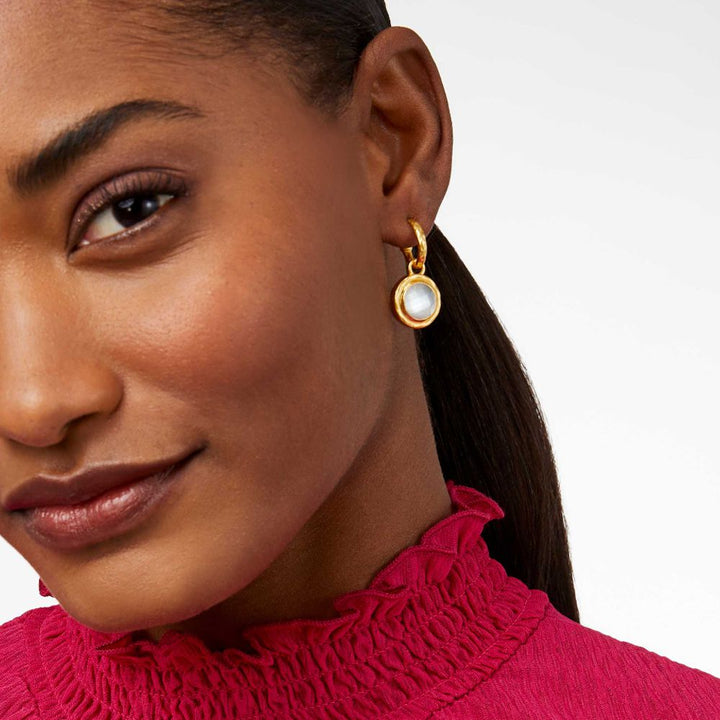 Gold hoop earrings with a pearly white stone pendant; close-up on model's ear.