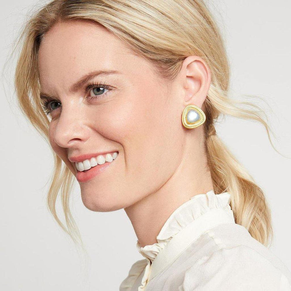 Triangular clip-on earrings featuring a pearly center and gold-toned accents, worn by a woman with blonde hair.