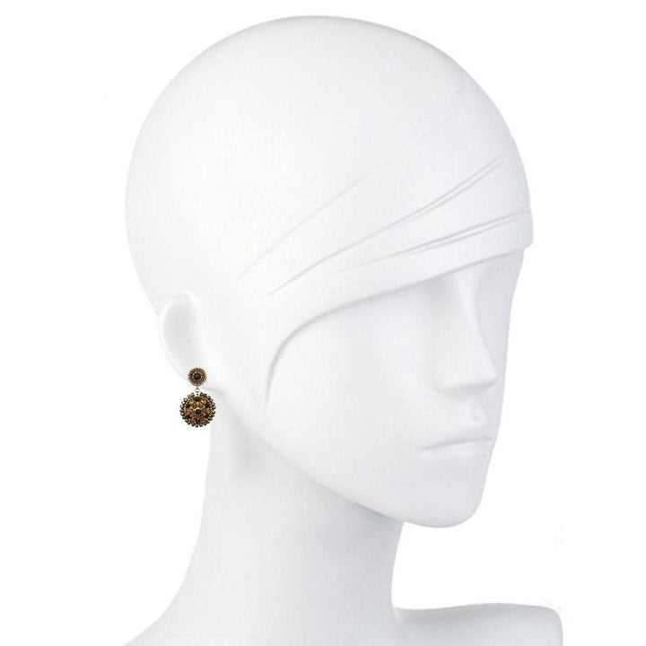Beaded drop earrings on a mannequin, showcasing ornate bronze detailing.