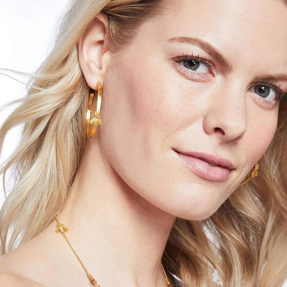 Gold bee hoop earrings on a model.