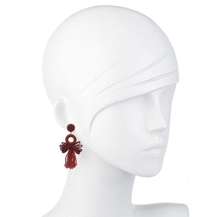 Red tassel earrings with a circular accent, displayed on a mannequin.