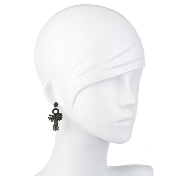 Dark grey tassel earrings on a mannequin, featuring a circular accent.