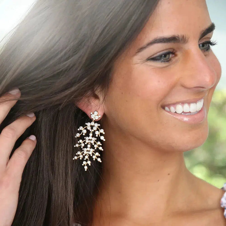 Sparkling crystal chandelier earrings, cascading design, worn by a woman with brown hair.