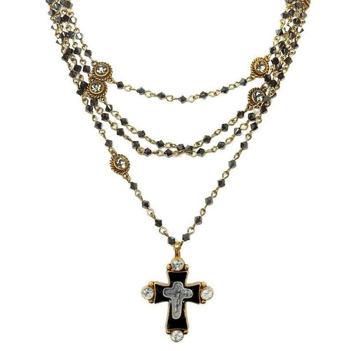 Layered black crystal and gold necklace featuring a detailed cross pendant.