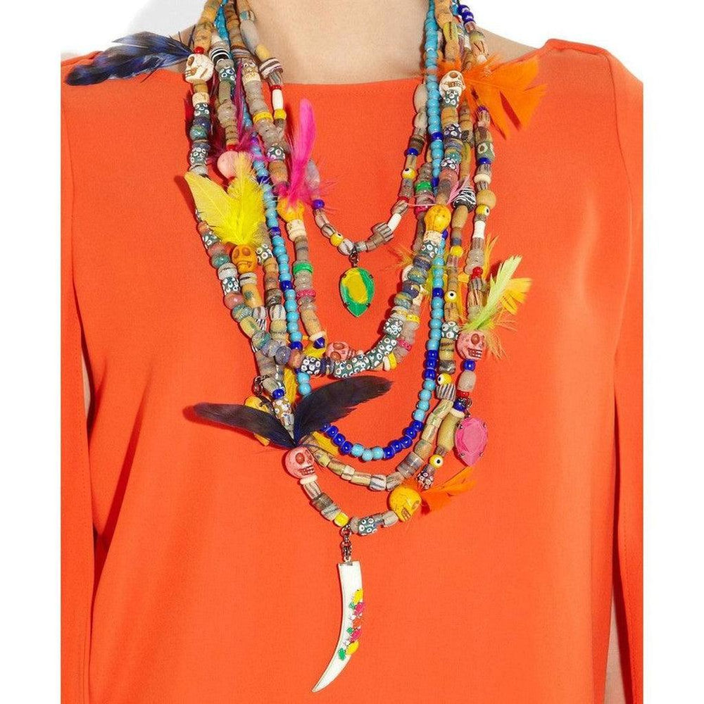 Multi-strand beaded necklace featuring colorful beads, skull accents, feathers, and a unique bone pendant, displayed against a vibrant orange background.