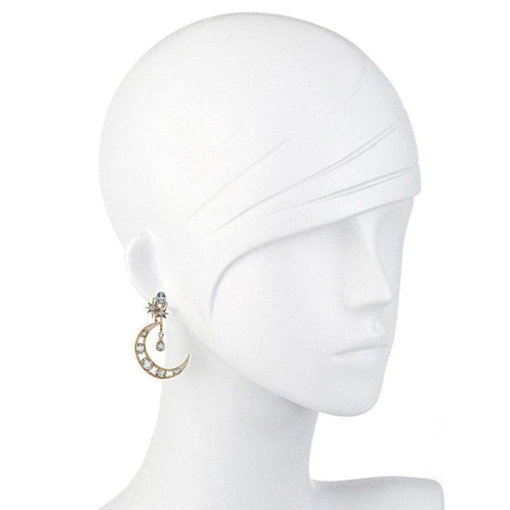Crescent moon earrings with blue topaz and star accents, displayed on a mannequin.