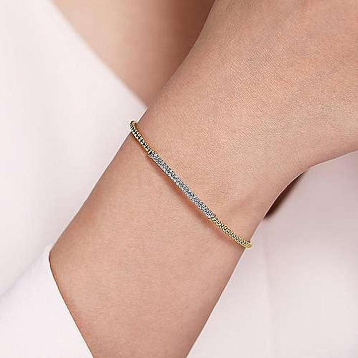 Yellow gold bracelet with pave diamonds, shown on a wrist.
