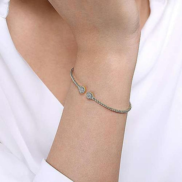 Gold bangle bracelet featuring two hexagon diamond accents.