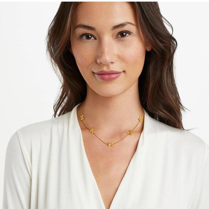 Gold butterfly necklace on model wearing cream top.