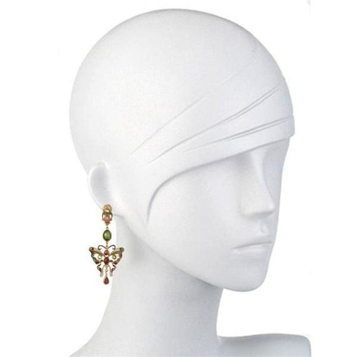 Gold butterfly earrings with pink and green gemstones dangling from a mannequin's ear.