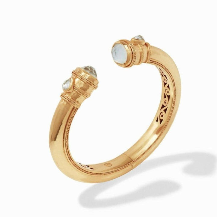 Gold cuff bracelet with clear gemstones, detailed etching, and a hinge.