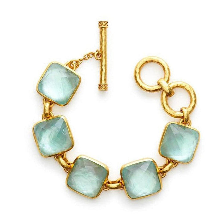 Gold chain bracelet featuring pale blue square gemstones; toggle clasp.