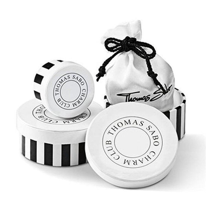 Coin charm in elegant black-and-white striped box, nestled in a satin pouch.