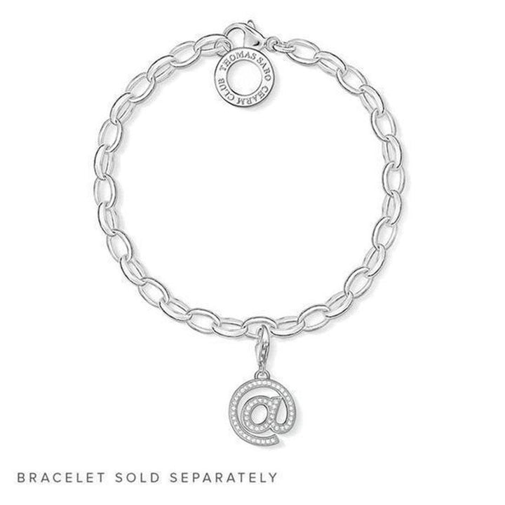 Silver ampersand charm with clear stones, hanging from a chain bracelet (sold separately).