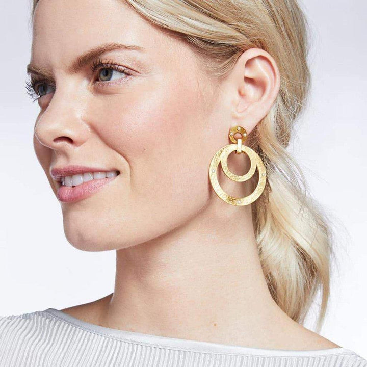 Gold double-circle statement earrings with textured metal and small accents.