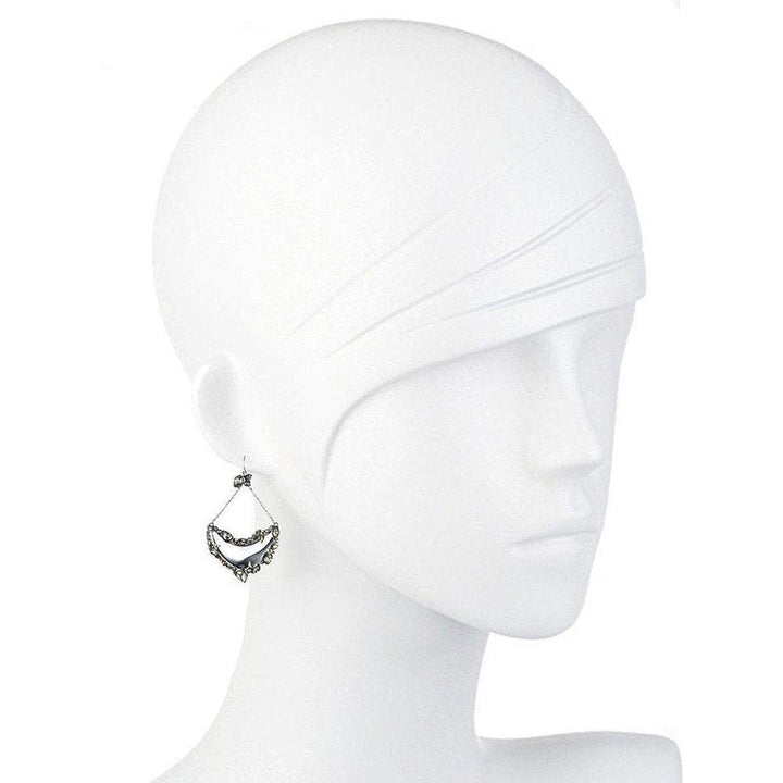 Silver crescent earrings displayed on a mannequin, featuring a crystal-framed design.