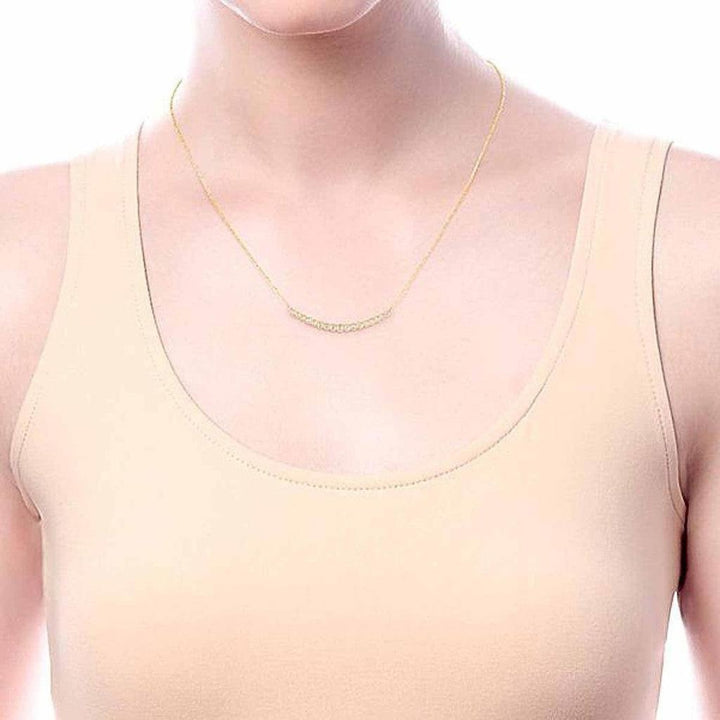 Gold chain necklace featuring a curved diamond bar, shown on a model.