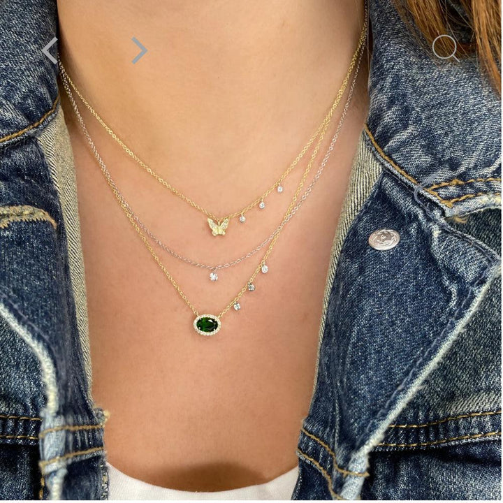 Layered necklaces featuring a diamond butterfly pendant and green gemstone.