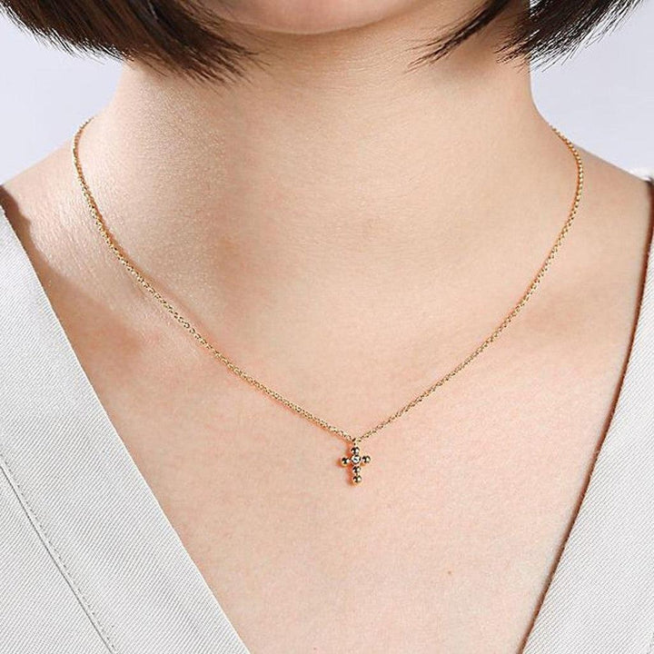 Dainty gold chain necklace featuring a small diamond-studded cross pendant.