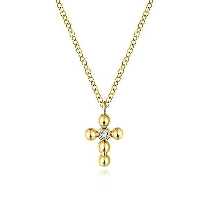 Delicate yellow gold cross necklace with a single diamond accent.