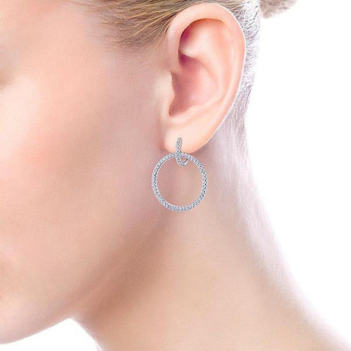 Diamond huggie hoop earrings on a woman's ear, close-up view.