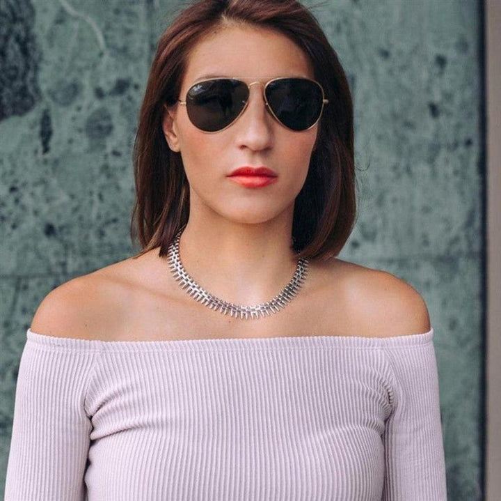 Silver statement necklace, textured design, worn with off-the-shoulder top.