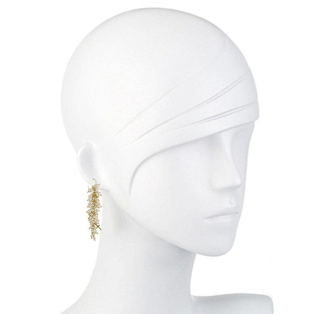 Gold-tone, cascading pearl earrings displayed on a white mannequin.