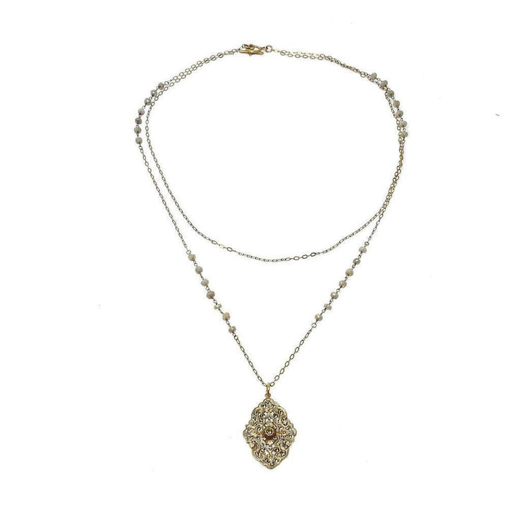 Gold layered necklace featuring an ornate medallion and delicate beaded chain.