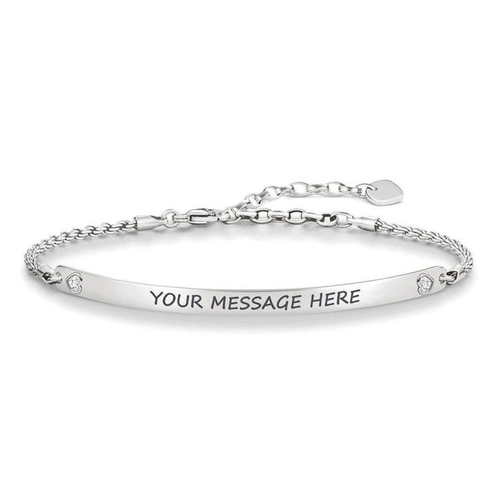 Silver ID bracelet with engraved message space, delicate chain, and small accents.