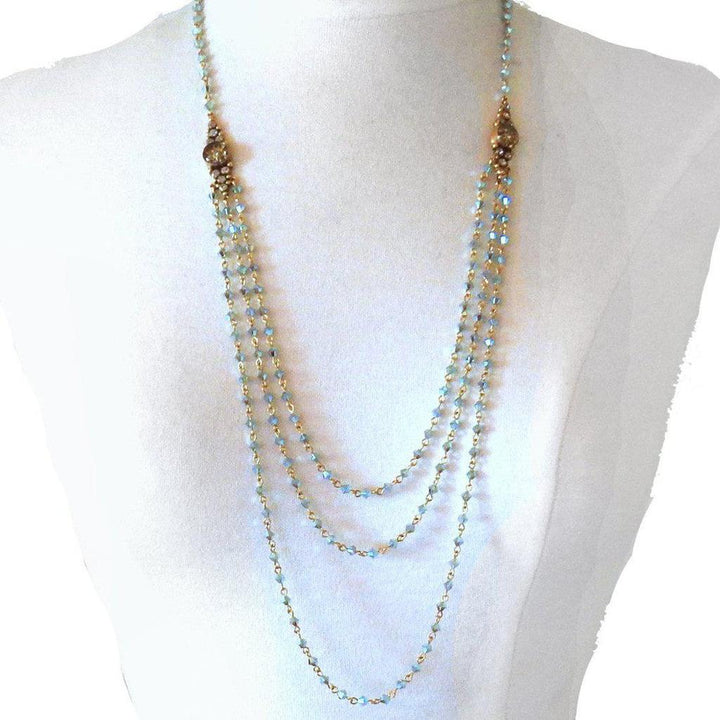 Layered pale blue crystal necklace with gold accents, displayed on a mannequin.