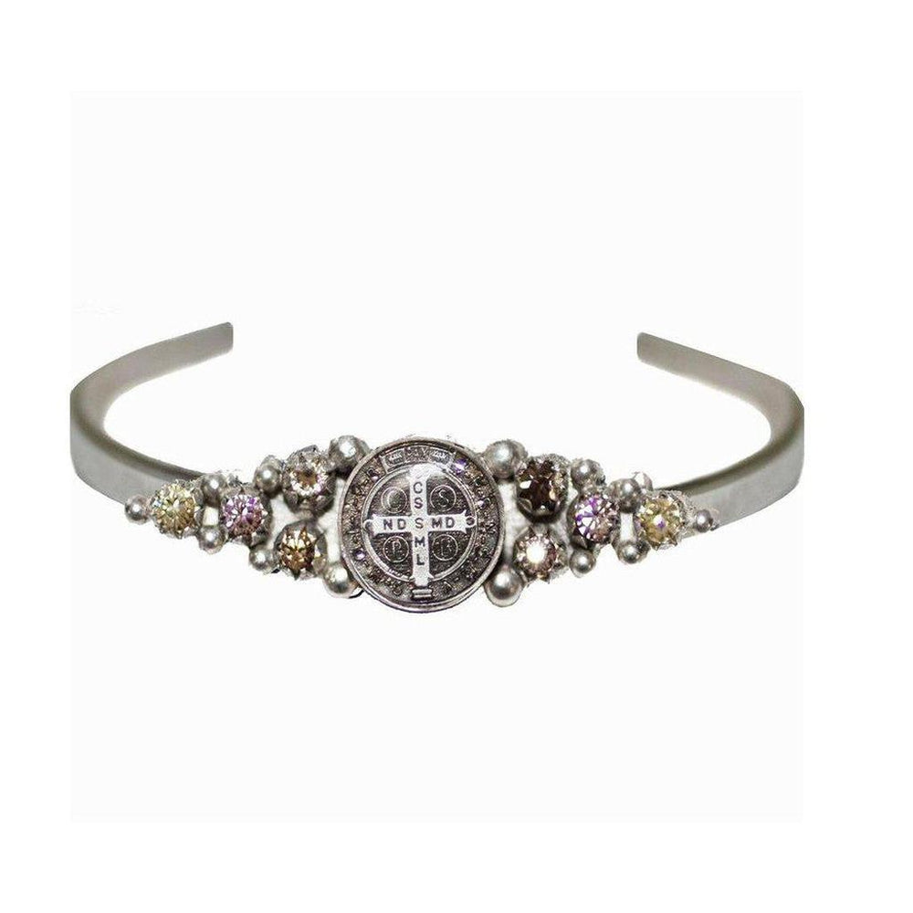 Silver cuff bracelet adorned with a religious medal and sparkling gemstones.