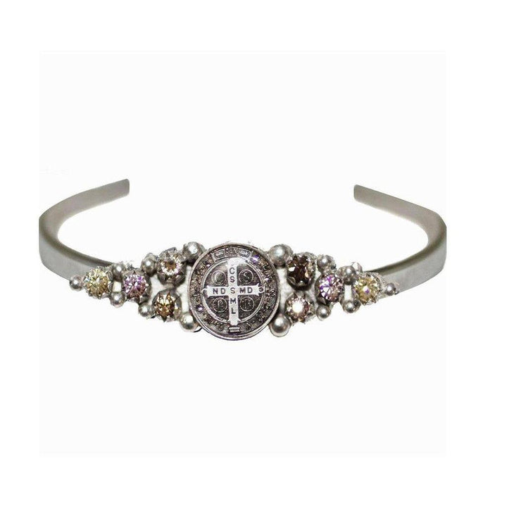 Silver cuff bracelet adorned with a religious medal and sparkling gemstones.