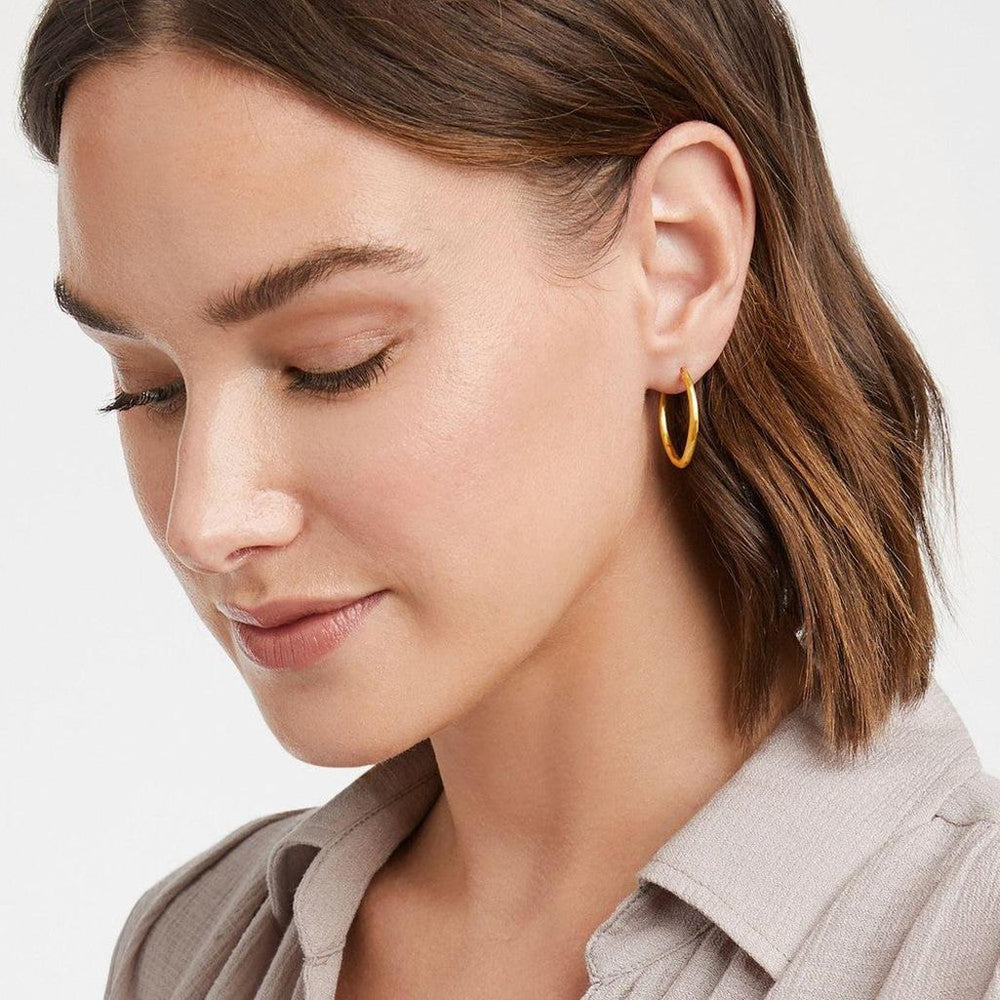 Gold double hoop earrings on a woman; simple, elegant style.