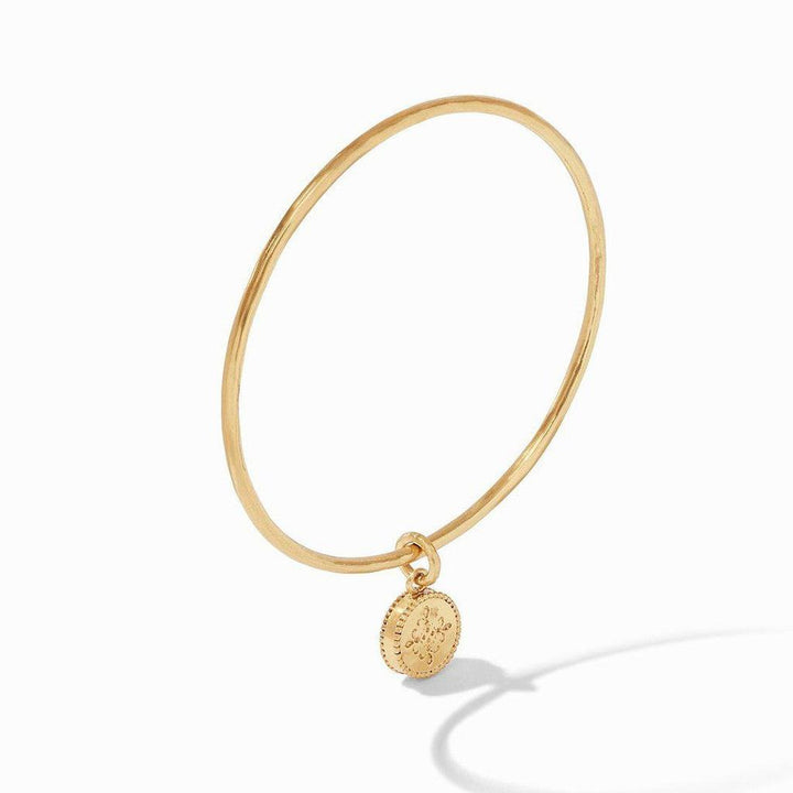 Gold bangle bracelet with a fleur-de-lis charm.