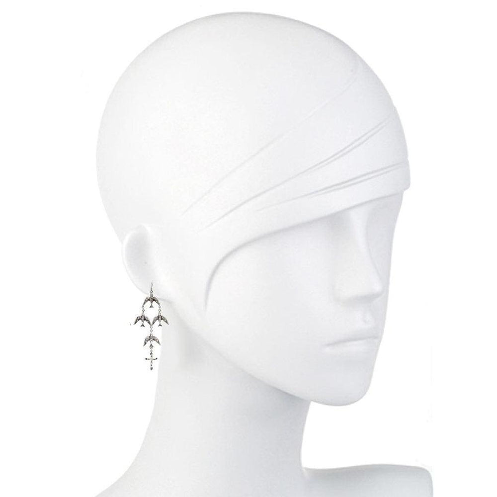Silver bird and cross dangle earrings on mannequin.