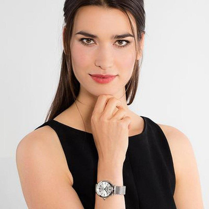 Woman's silver mesh watch with white face, elegantly displayed.