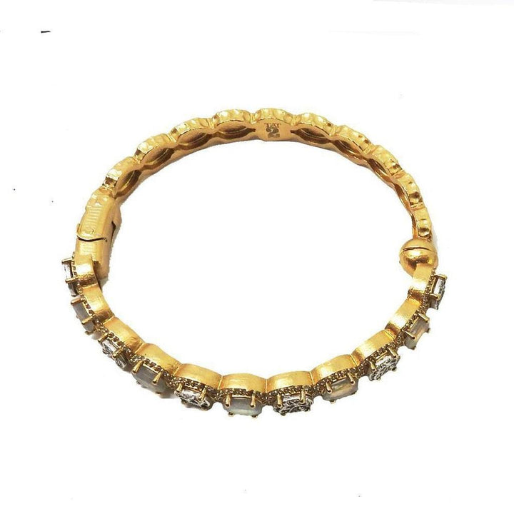 Gold hinged bangle bracelet adorned with sparkling stones.