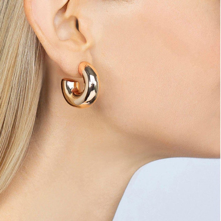 Gold hoop earrings on model's earlobe.