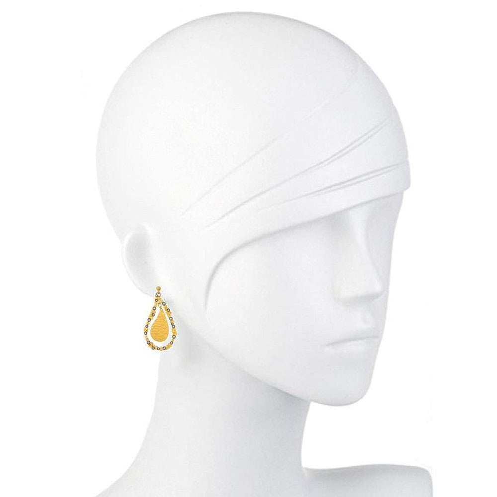 Teardrop-shaped gold earrings with diamond accents, showcased on a mannequin.