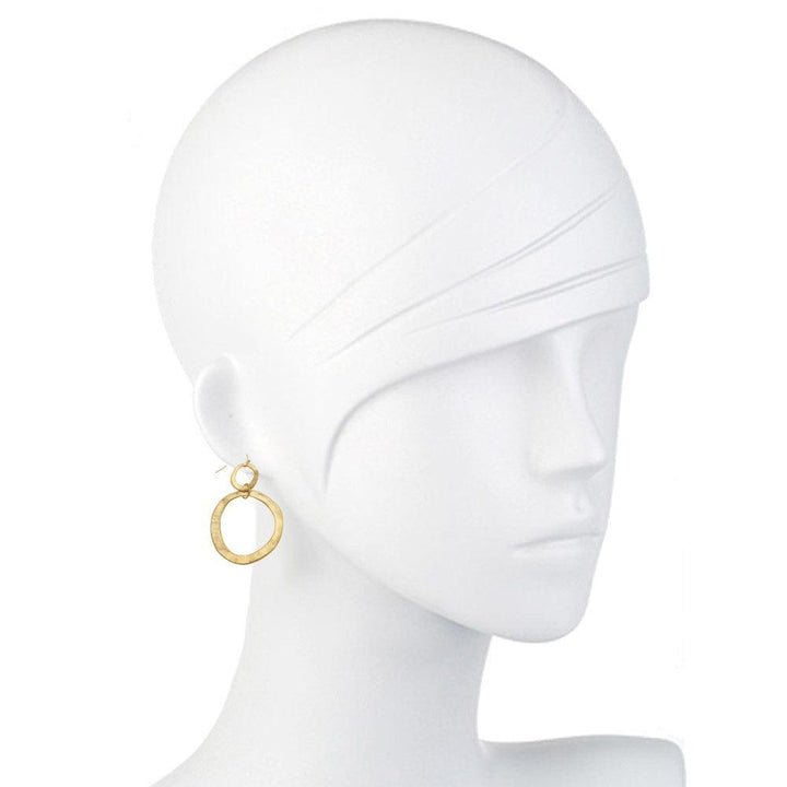 Gold hammered hoop earrings on a mannequin.