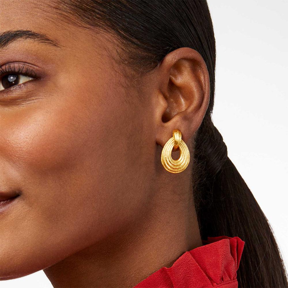 Gold doorknocker earrings with textured detail, worn by a model.