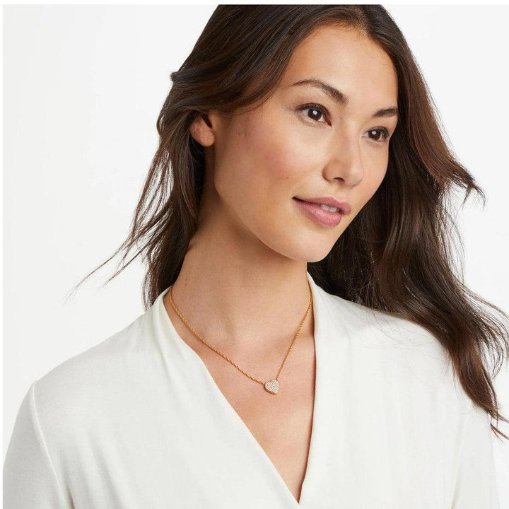 Gold chain necklace featuring a small, pave-set heart pendant on a woman.